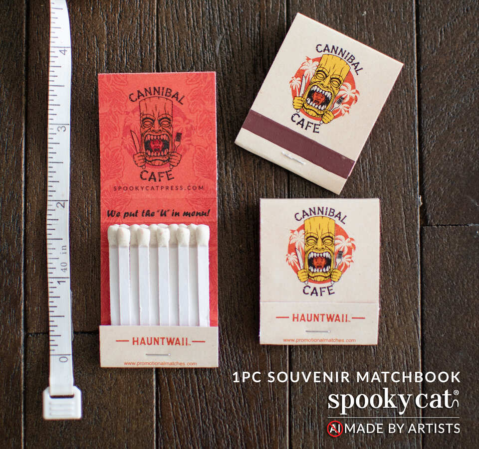 Vintage-style Cannibal Cafe souvenir matchbook featuring a hungry tiki idol illustration and functional safety matches from Hauntwaii.