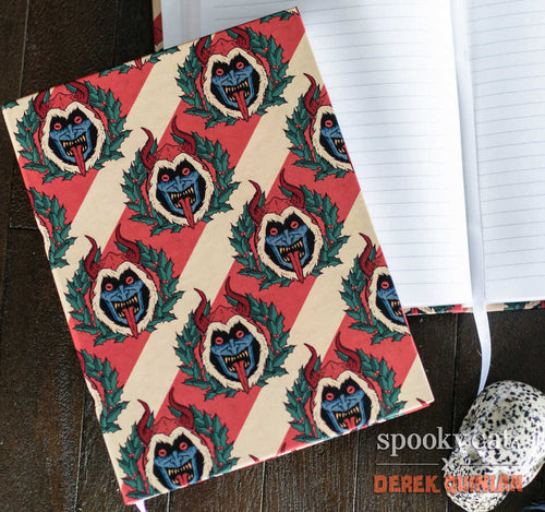Krampus journal with a repeating pattern of blue-faced Krampus heads framed by holly on red and cream candy-cane stripes.