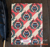 Vintage-style hardcover notebook featuring Derek Quinlan’s Krampus wreath pattern with red, cream, and green holiday design.
