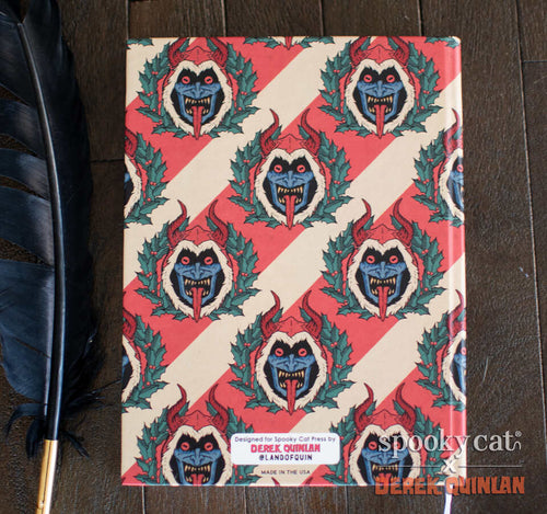 Vintage-style hardcover notebook featuring Derek Quinlan’s Krampus wreath pattern with red, cream, and green holiday design.