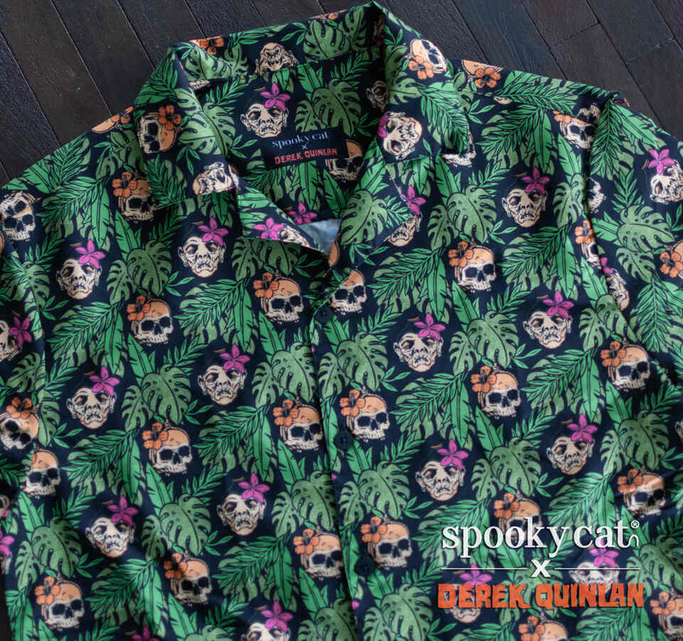 Close-up detail of the black Tiki Shrunken Head Button-Up Shirt pattern featuring skulls, shrunken heads, tropical leaves, and island flowers.