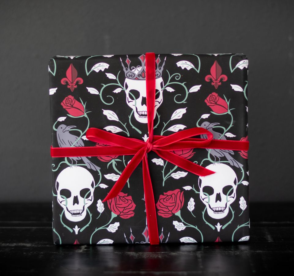 Skulls crowns and faded red roses on a dark black wrapping paper